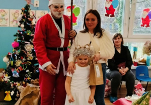 Dziewczynka z mamą pozuje do zdjęcia z Mikołajem