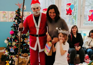 Dziewczynka z mamą pozuje do zdjęcia z Mikołajem