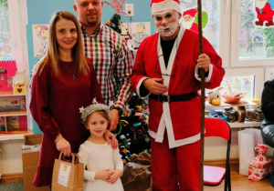 Dziewczynka z rodzicami pozuje do zdjęcia z Mikołajem