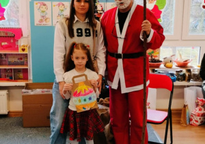 Dziewczynka z mamą pozuje do zdjęcia z Mikołajem