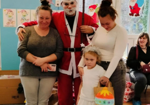 Dziewczynka z mamą i babcią pozuje do zdjęcia z Mikołajem
