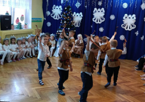 Grupa chłopców w przebraniu pasterzy tańczy z ciupagami