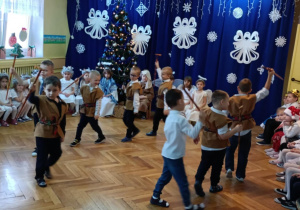 Grupa chłopców w przebraniu pasterzy tańczy z ciupagami