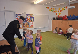 Górnik w stroju galowym częstuje dzieci cukierkami z okazji swojego święta