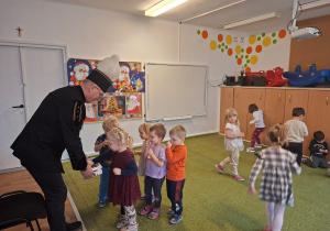 Górnik w stroju galowym częstuje dzieci cukierkami z okazji swojego święta