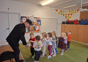 Górnik w stroju galowym częstuje dzieci cukierkami z okazji swojego święta