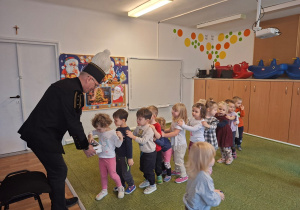 Górnik w stroju galowym częstuje dzieci cukierkami z okazji swojego święta