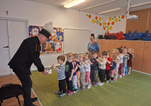 Górnik w stroju galowym częstuje dzieci cukierkami z okazji swojego święta