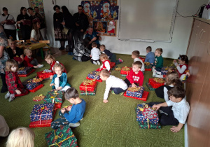 Dzieci rozpakowują prezenty otrzymane od Mikołaja