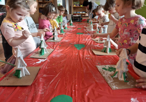 Dzieci malują wykonane przez siebie choinki z gipsowych klocków