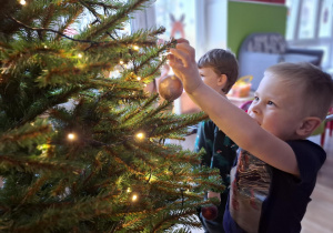 Chłopiec wiesza bombkę na choince