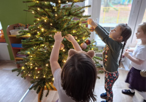 Dzieci wieszają bombki na choince