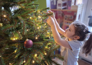 Dziewczynka wiesza bombkę na choince