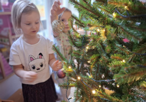 Dziewczynki wieszają bombki na choince