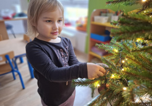 Dziewczynka wiesza bombkę na choince