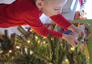 Chłopiec wiesza bombkę na choince