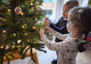 Dziewczynki wieszają bombki na choince