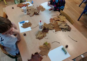 Dzieci tworzą kompozycję z liści i kasztanów