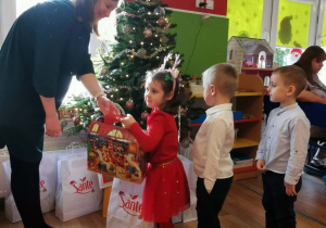 Nauczycielka rozdaje dzieciom paczki świąteczne
