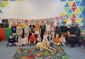 Dzieci pozują do zdjęcia z przedstawicielem Straży Miejskiej