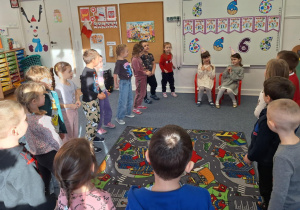 Justyna i Marcelina siedzą na krzesełkach, reszta dzieci śpiewa im 100 lat