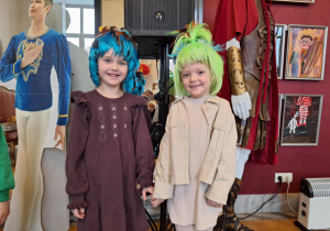 Dziewczynki pozują do zdjęcia w teatralnych perukach