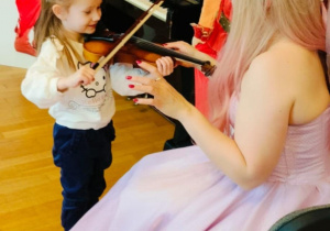 Dziewczynka próbuje grać na skrzypcach