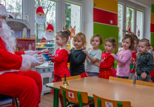 Dzieci ustawione "w pociąg" odbierają upominki od Świętego Mikołaja