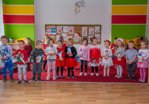 Dzieci pozują do zdjęcia trzymając upominki od Świętego Mikołaja