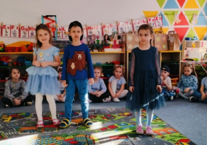 Grupa dzieci stoi na dywanie i recytuje wiersz