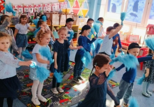 Dzieci na dywanie tańczą z pomponami