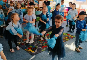 Dzieci na dywanie tańczą z pomponami