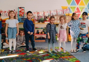 Grupa dzieci stoi na dywanie i recytuje wiersz
