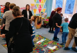 Babcie i dziadkowie tańczą na dywaniez wnukami