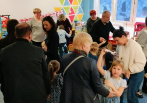 Babcie i dziadkowie tańczą na dywaniez wnukami