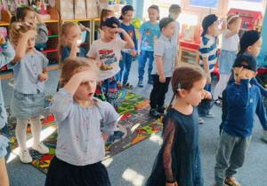 Dzieci stoją na dywanie i śpiewają piosenkę