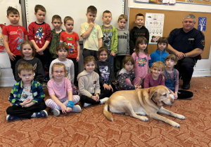 Grupa dzieci z strażnikiem miejskim i psem