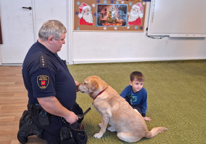 Dziecko głaszcze psa pod nadzorem strażnika