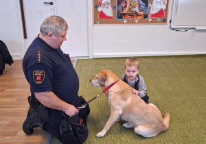 Dziecko głaszcze psa pod nadzorem strażnika