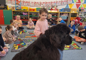 Dziewczynka głaszcze siedzącego psa