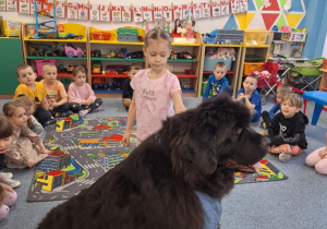 Dziewczynka głaszcze siedzącego psa