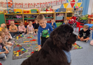 Chłopiec głaszcze siedzącego psa