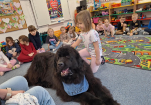 Dziewczynka głaszcze siedzącego psa