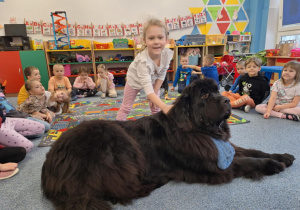 Dziewczynka głaszcze siedzącego psa