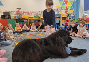 Dziewczynka głaszcze siedzącego psa