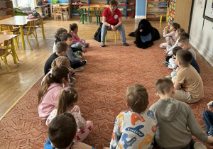 W kole siedzą dzieci, pani i pies