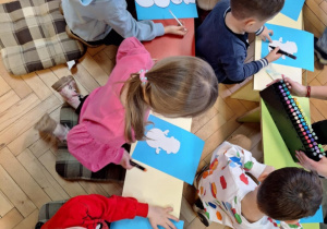 Grupa dzieci wykonuje prace plastyczną -bałwanka