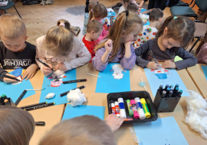 Grupa dzieci wykonuje prace plastyczną -bałwanka