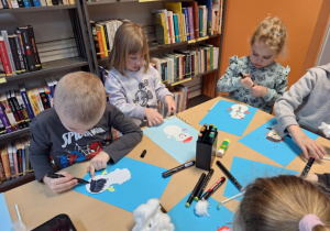 Grupa dzieci wykonuje prace plastyczną -bałwanka