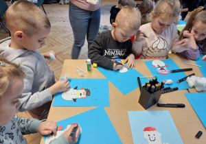 Grupa dzieci wykonuje prace plastyczną -bałwanka